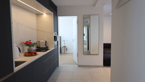 A modern kitchen with a marble countertop, a coffee machine, and a vase with flowers. - Apartment 22 (München)