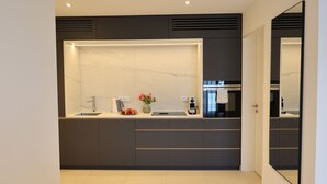 A modern kitchen with a built-in stove, a sink, and a countertop with a vase of flowers. - Apartment 22 (München)