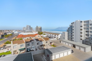 Zona residencial costera con edificios modernos, un estacionamiento y vistas al océano.