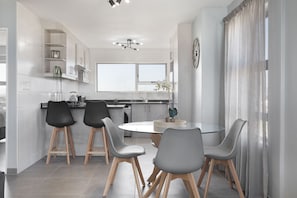 A modern kitchen with a dining area, featuring a round table and bar stools.