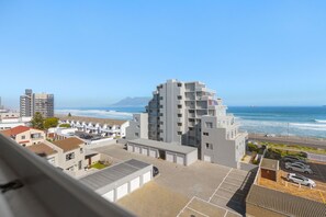 A modern building with a unique architectural design, featuring multiple balconies and a parking area in front. - Ocean View 503 (Cape Town)