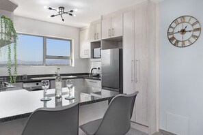 A modern kitchen with a large island, stainless steel appliances, and a large wall clock.