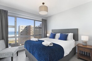 Una habitación de hotel moderna con una cama grande, vistas a la ciudad y una ventana con cortinas.