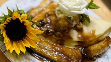 A plate with a dish of glazed meat, a white rose, and a sunflower.