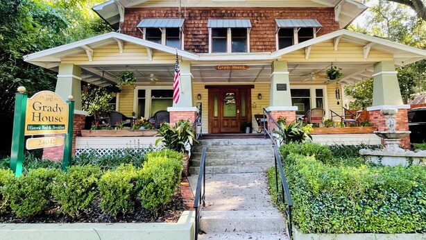 A historic bed and breakfast with a covered front porch, a sign indicating 'Grady House', and a flag. - Grady House Bed & Breakfast (High Springs)