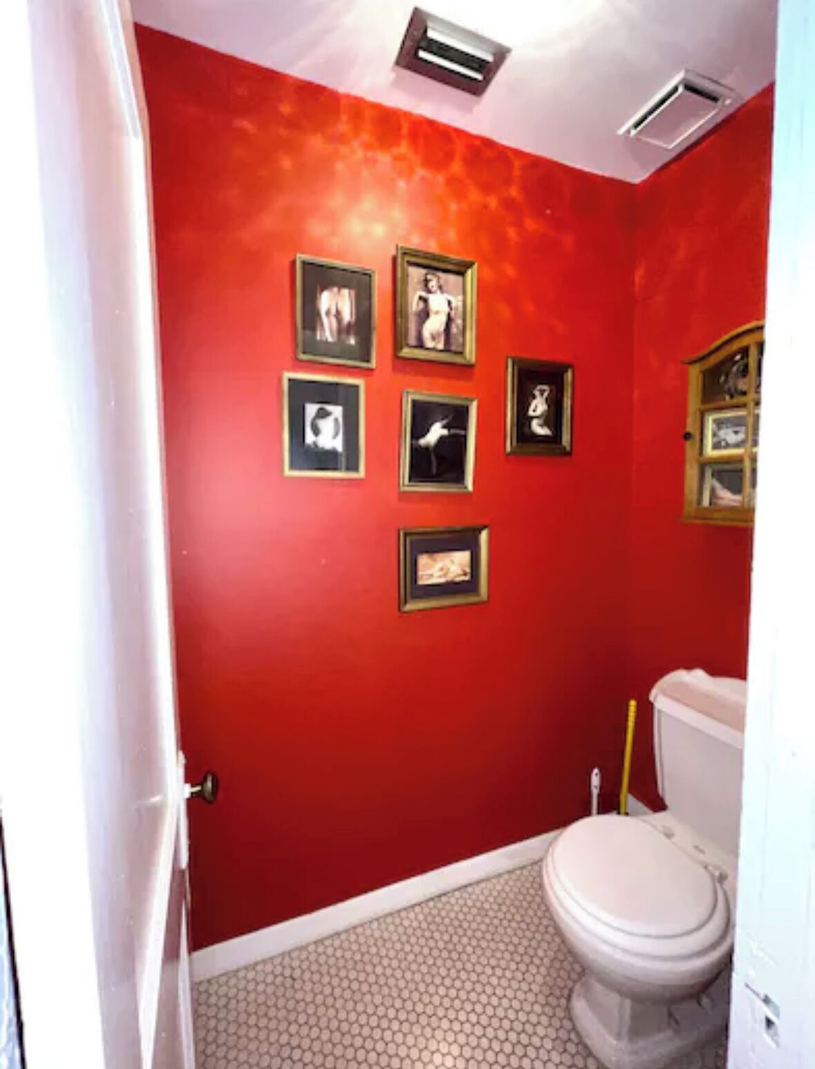 A bathroom with red walls, a white toilet, and hexagonal patterned floor tiles.