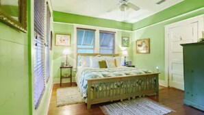 A bedroom with a bed, a nightstand, a dresser, a ceiling fan, and a window with blinds. - Grady House Bed & Breakfast (High Springs)