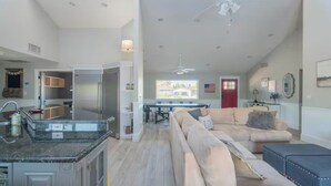 Amplia sala de estar con un sofá grande, una mesa de comedor y una cocina con refrigerador y armarios.