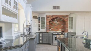 A spacious kitchen with white cabinetry, a central island, and a brick backsplash. - Entertainer's Dream Home! 3 Bdrm, Pool, Games! (Phoenix)