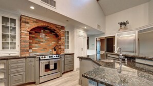 Una cocina con arco de ladrillo, electrodomésticos de acero inoxidable y encimera de granito.