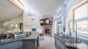 A spacious kitchen with a large island, a brick fireplace, and a ceiling fan. - Entertainer's Dream Home! 3 Bdrm, Pool, Games! (Phoenix)