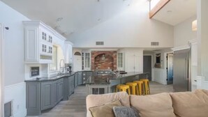 A spacious kitchen with a central island, grey cabinets, and a brick fireplace. - Entertainer's Dream Home! 3 Bdrm, Pool, Games! (Phoenix)