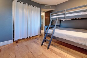 A bunk bed room with a wooden floor, a white curtain, and a door in the background. - Entertainer's Dream Home! 3 Bdrm, Pool, Games! (Phoenix)