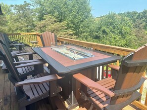 A deck with a glass-top table and wooden chairs. - Bright 2-bedroom lake view home (Scio)