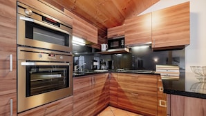 Eine moderne Küche mit Edelstahlgeräten, Holzschränken und Fliesenboden.