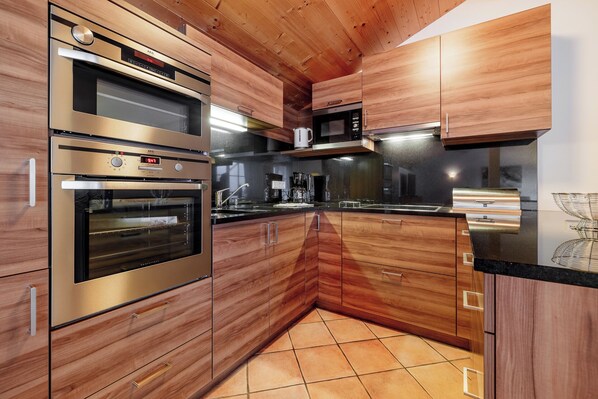 Una cocina moderna con electrodomésticos de acero inoxidable, armarios de madera y piso de baldosas.