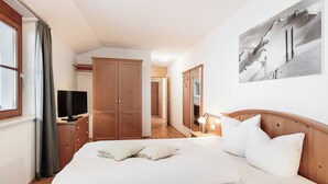 Ein Schlafzimmer mit einem großen Bett, einem Holzschrank und einem Fernseher auf einem Nachttisch.