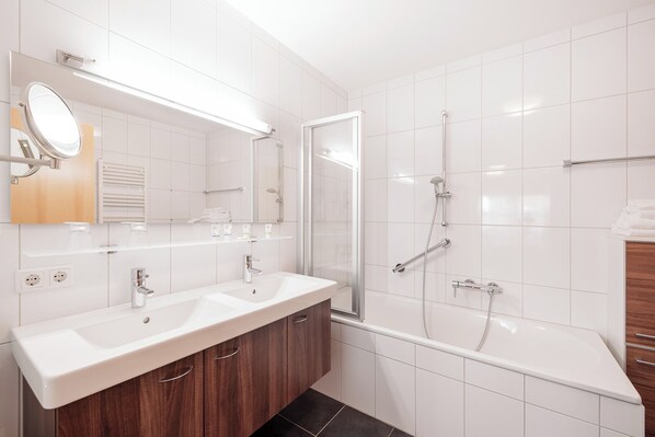 A modern bathroom with two sinks, a shower, and a bathtub.