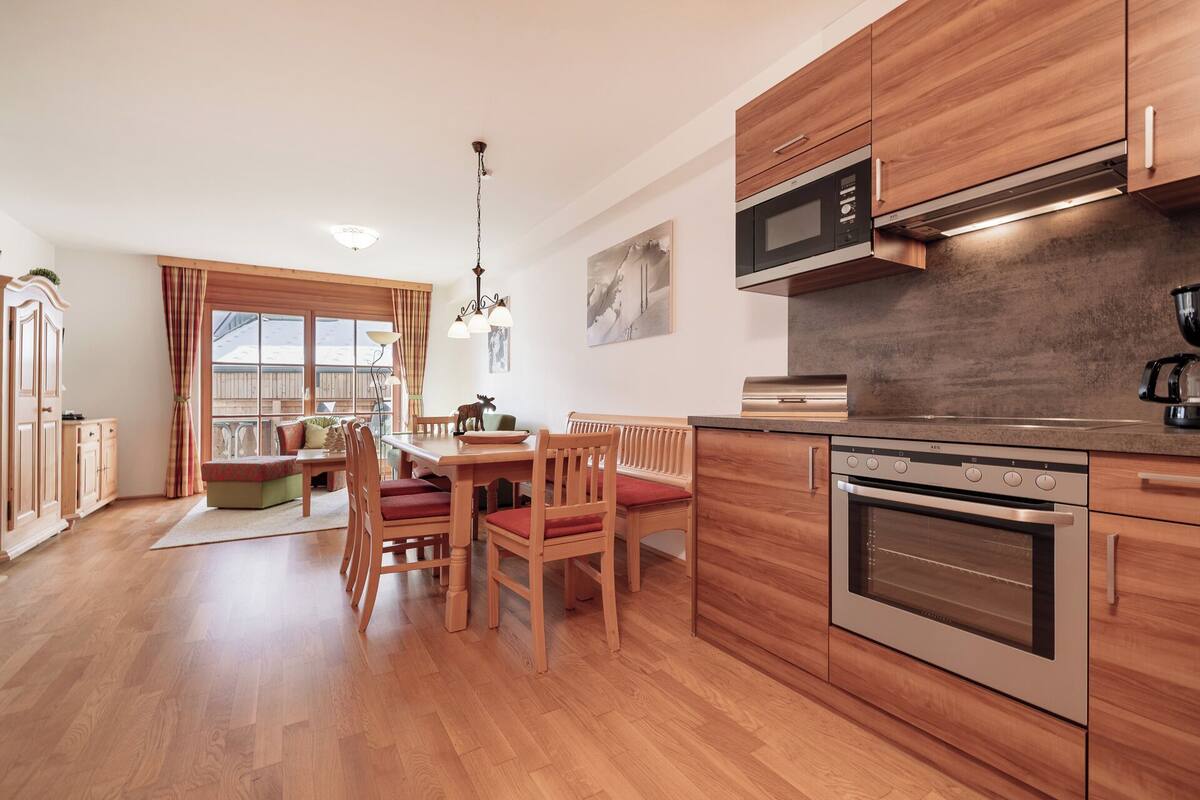 A modern kitchen with wooden cabinets, a built-in oven, and a microwave.