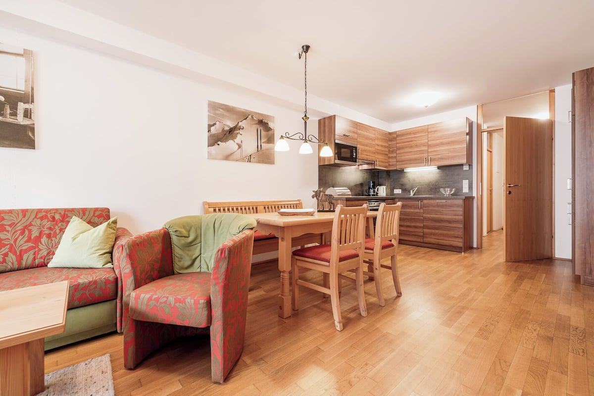 A compact living space with a dining area, kitchenette, and a sofa with patterned upholstery.