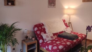 A cozy room with a red patterned sofa, a lamp, and a small table with a plant. - Grand Chalet (Brides-les-Bains)