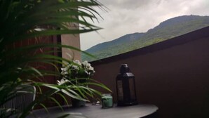 A round table with a lantern and a potted plant on a balcony with a view of a green hill. - Grand Chalet (Brides-les-Bains)