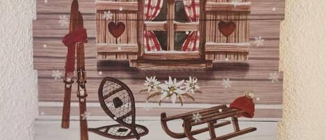 A rustic wooden wall with a window, a red coat, a sled, and a pair of skis.
