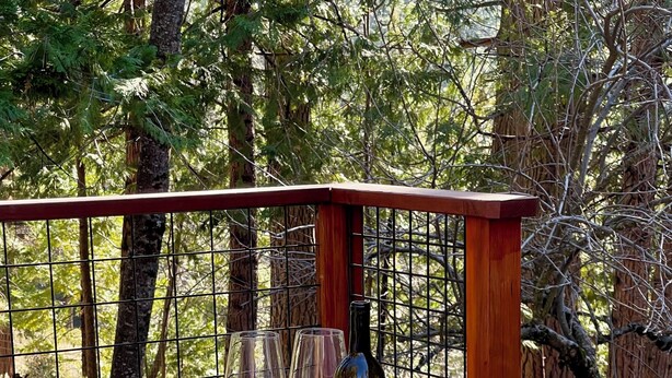 A hot tub with a wooden deck, surrounded by trees.