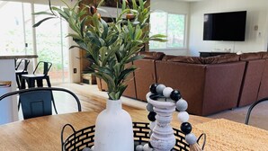 A dining area with a table set for two, featuring a woven placemat, a white vase with green plants, and a decorative candle holder.