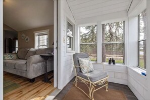 Relax in a serene space with a sofa, armchair, and dining table near a large window offering a view of the outdoors.