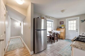 Compact kitchen area with a refrigerator, dining table, and sink.