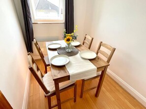 Uma mesa de jantar posta, com pratos, um vaso de flores e um jogo americano.