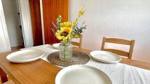 A dining table with two white plates, a clear glass vase with yellow flowers, and a woven placemat. - Lovely 2-bed Tree-hole in Northolt Southharrow (Northolt)