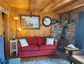 L’intérieur d’un chalet accueillant, avec un canapé rouge, une horloge, un tableau et une pancarte indiquant « FERMÉ AUJOURD’HUI ».