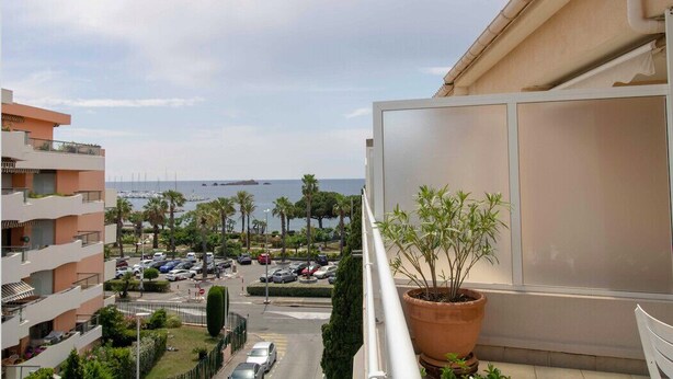 A balcony with a potted plant, overlooking a parking area and a view of the sea. - Bright cocoon with terrace and sea view (Saint-Raphaël)