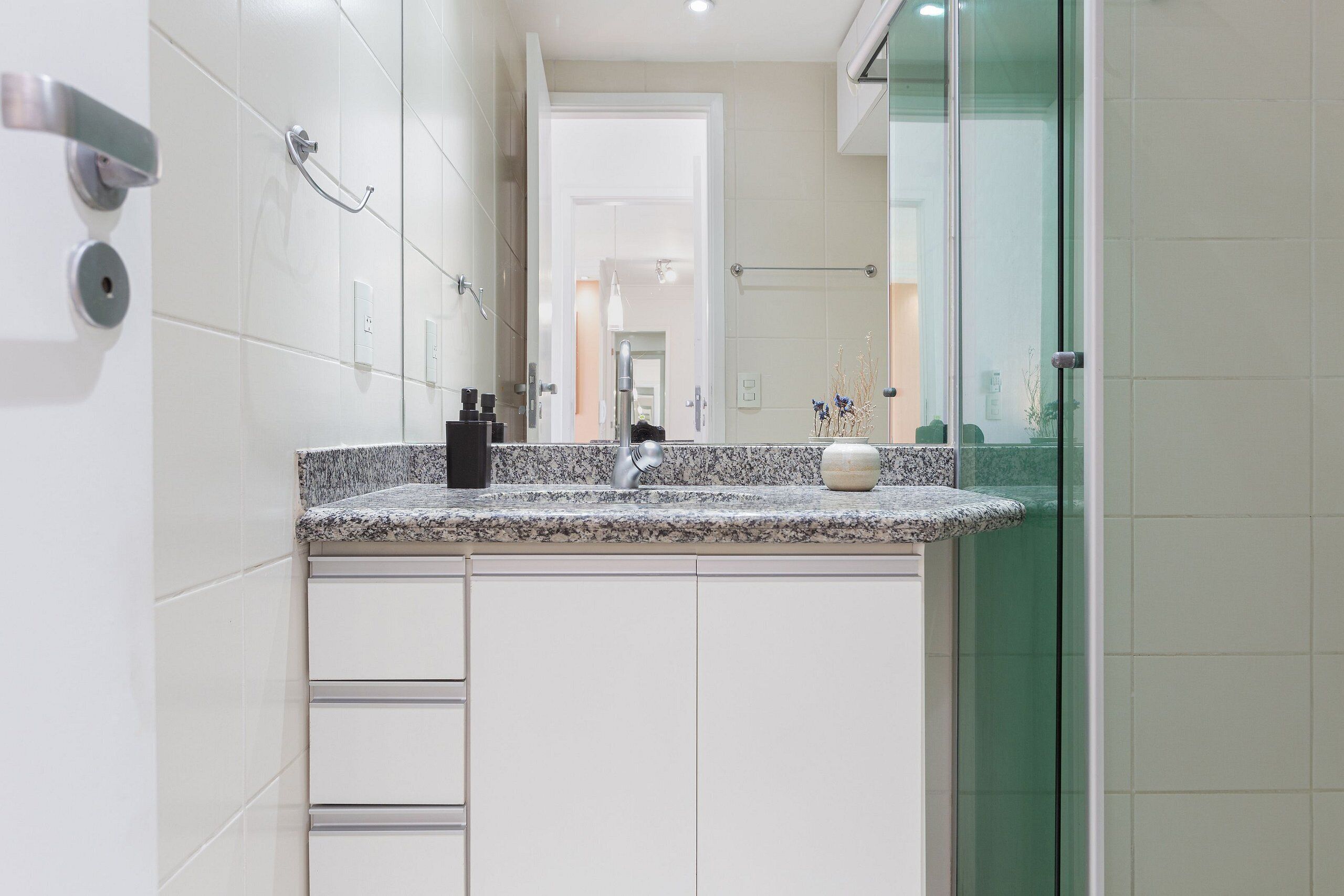 Un baño moderno con encimera de granito, un espejo y cabina de ducha de vidrio.
