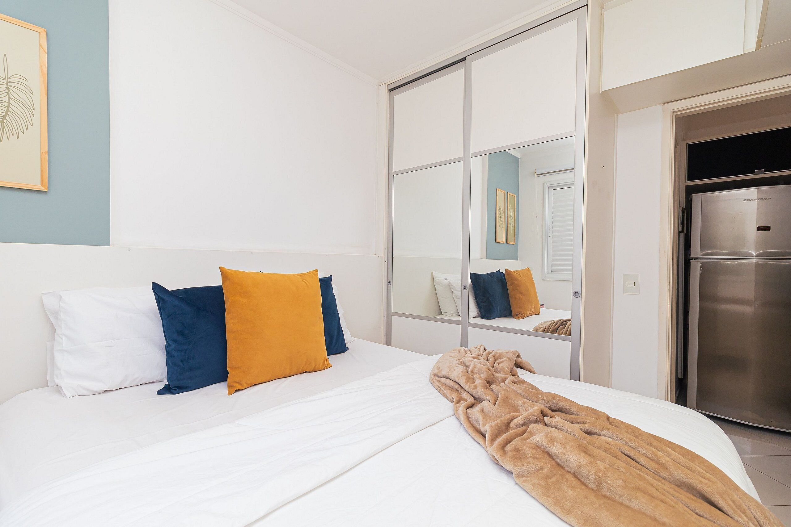 Une chambre d’hôtel équipée d’un lit, d’un miroir, d’une armoire et d’un réfrigérateur.