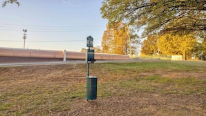 A green metal structure with a sign, a fenced area, and trees in the background.