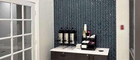 A bathroom with a white door, a mirror, and a vanity with a black cabinet and drawers.