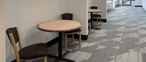Käytävän lattia on peitetty matolla, ja siellä on useita pyöreitä pöytiä ja tuoleja.