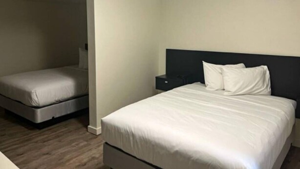Una habitación de hotel con una cama grande, una cama más pequeña, una mesita de noche y un televisor.