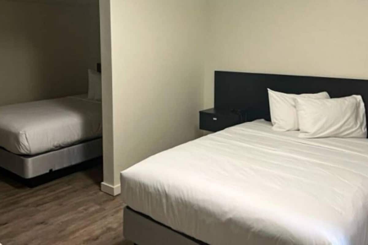 Una habitación de hotel con una cama grande, una cama más pequeña, una mesita de noche y un televisor.