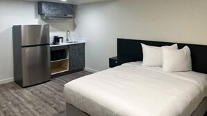 Una habitación de hotel con una cama, una kitchenette pequeña y un horno empotrado.