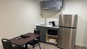 Cocina compacta con refrigerador de acero inoxidable, microondas y cafetera sobre la encimera.