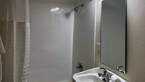 Un baño con ducha, lavamanos y espejo.