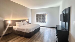 A modern hotel room with a large bed, a flat-screen TV, and a small desk. - Studio 6 Elkhart, IN- Kitchenette Rooms (Elkhart)