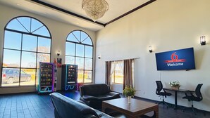 A spacious lobby with leather seating, a large TV screen displaying '6 motel + studio Welcome', and vending machines. - Studio 6 Elkhart, IN- Kitchenette Rooms (Elkhart)