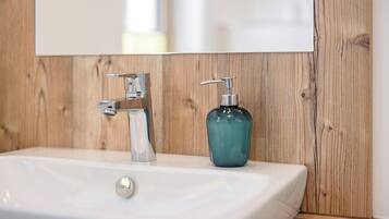 A bathroom with a white sink, a faucet, and a teal soap dispenser.