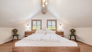 A bedroom with a wooden bed, two windows, and bedside lamps. - MYALPS Mühlhof (Oetz)