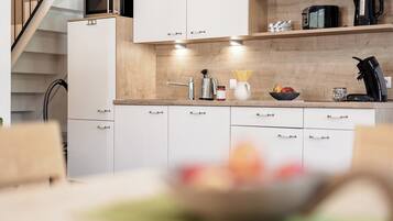 Een moderne keuken met witte kastjes, een houten aanrechtblad en een inbouwmagnetron.